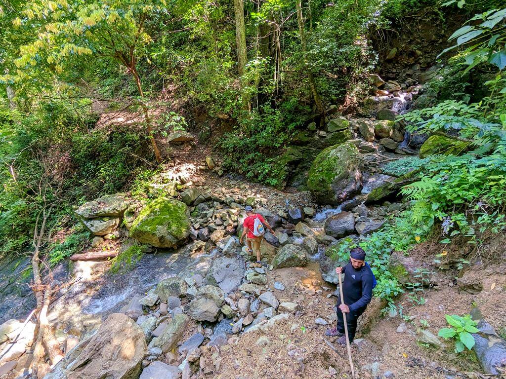 Baquiano assists hikers while crossing a rocky creek section on the Boquerones trail.