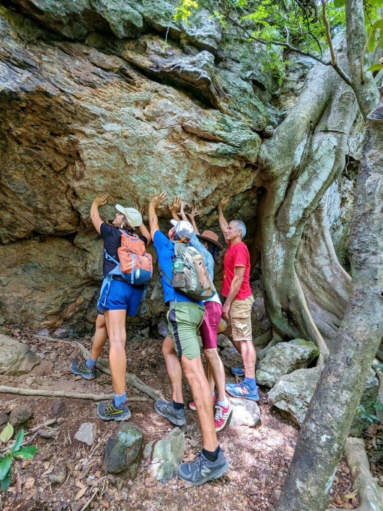 Hikers playfully posing as if preventing a large boulder from rolling down, during their journey on the El Encanto trail.