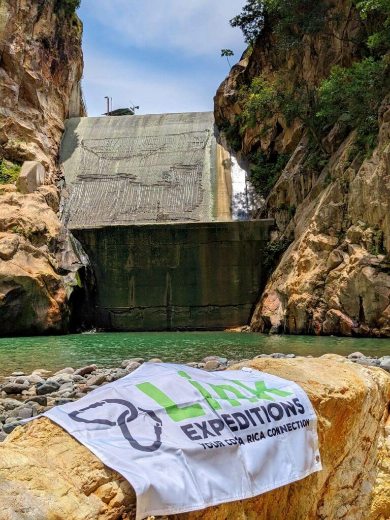 Link Expeditions flag displayed on a rock with the backdrop of El Encanto at the Aranjuez River canyon.