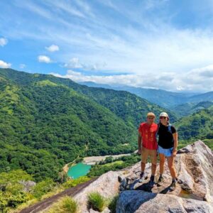 Two hikers atop a towering rock with a panoramic view of El Encanto Hydroelectric dam to the north.