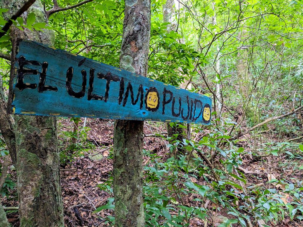 Signpost reading 'El Ultimo Pujido', indicating the final uphill challenge on the El Encanto Loop trail.