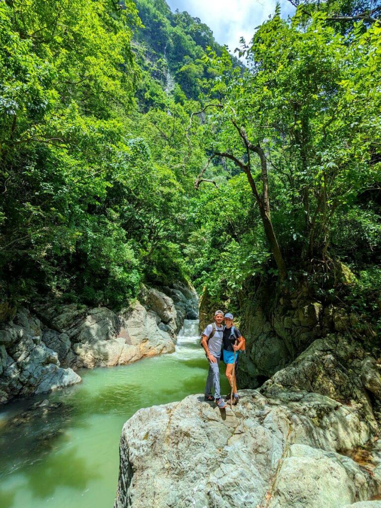 Hikers posing on large riverside rocks amidst the lush green backdrop of Boquerones.