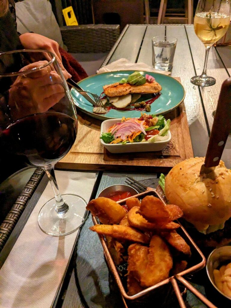 Plates from Alma de Arbol restaurant in San Gerardo de Dota, displaying fried potato wedges, hamburger, sauces, and a trout fillet with salad.