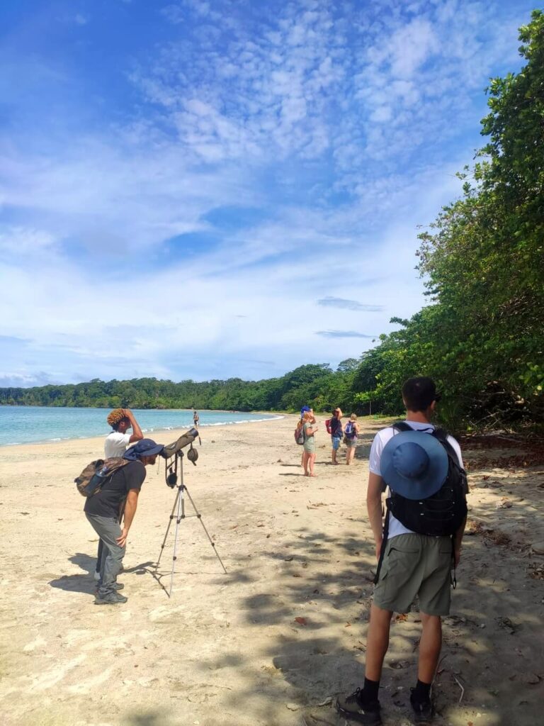 Tour guide at Cahuita National Park's beach in Costa Rica offering his telescope for visitors to view local wildlife.