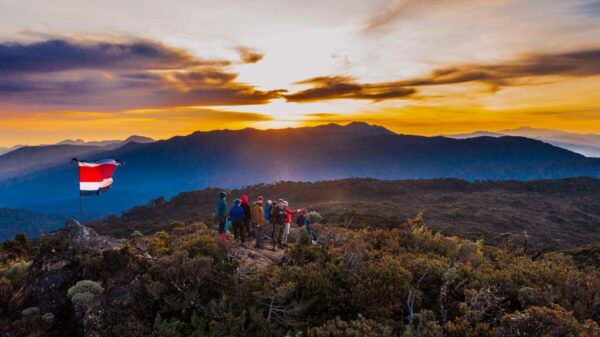 Captivating sunrise from the mountain top of Cerro Ena, nestled among Costa Rica's highest peaks. The image captures the Paramo, towering mountains, the undulating Costa Rican flag, and the radiant ascent of the sun.