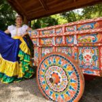 Woman with typical Costa Rican costume posing next to a cart, representing Costa Rican folklore.