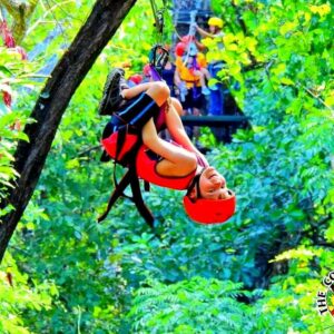 A young boy venturing on a canopy tour, sliding headfirst down the cable through the vegetation.
