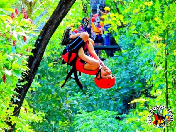 A young boy venturing on a canopy tour, sliding headfirst down the cable through the vegetation.
