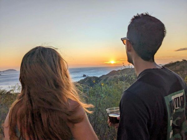 Couple enjoying a glass of wine while watching the sunset over the sea.