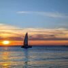 Boat sailing in the blue sea with a sunset painting the sky in warm colors.