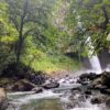 View of La Fortuna Waterfall from downstream, highlighting the clear waters, volcanic rocks, and lush forest.