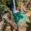 Aerial view of waterfall with crystalline waters and access bridges.