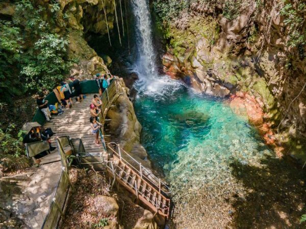 Aerial view of waterfall with crystalline waters and access bridges.