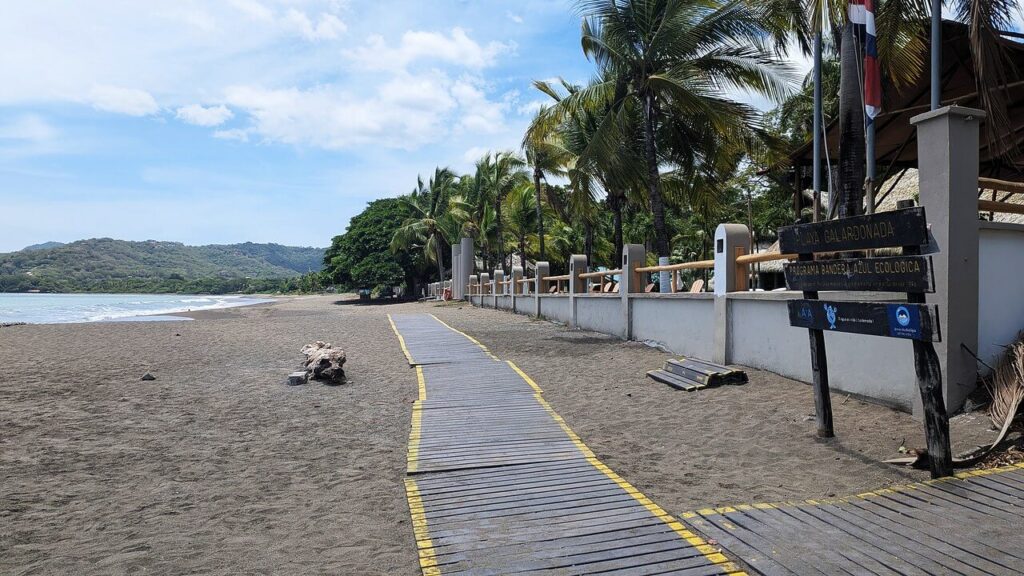 Calm Potrero Beach with golden sand, coconut palms, and blue skies over a protected bay in Guanacaste, Costa Rica — ideal for families